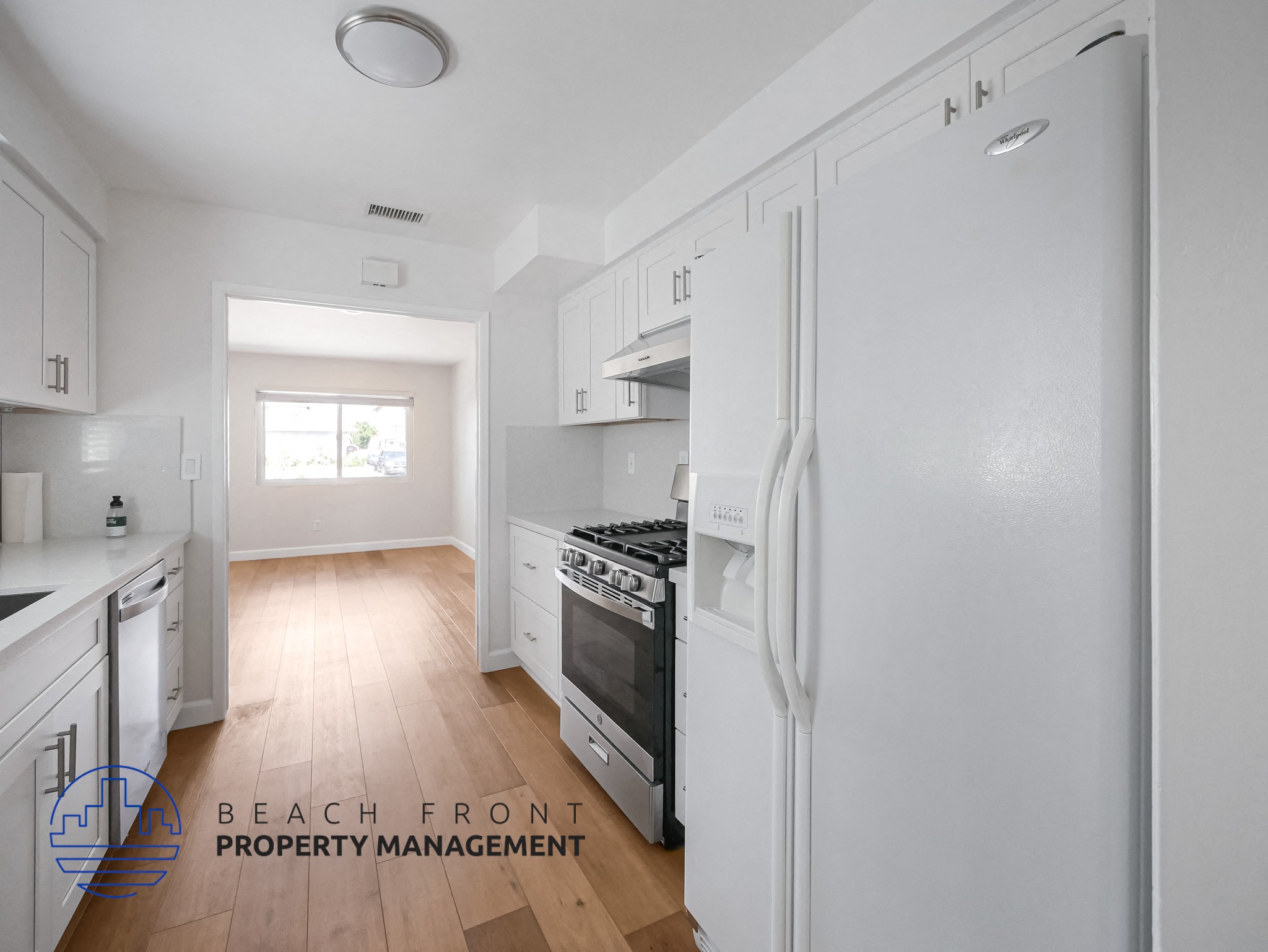 A kitchen with white appliances and wooden floors.